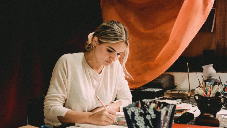 devojka sedi za stolom i fokusirana je na pisanje